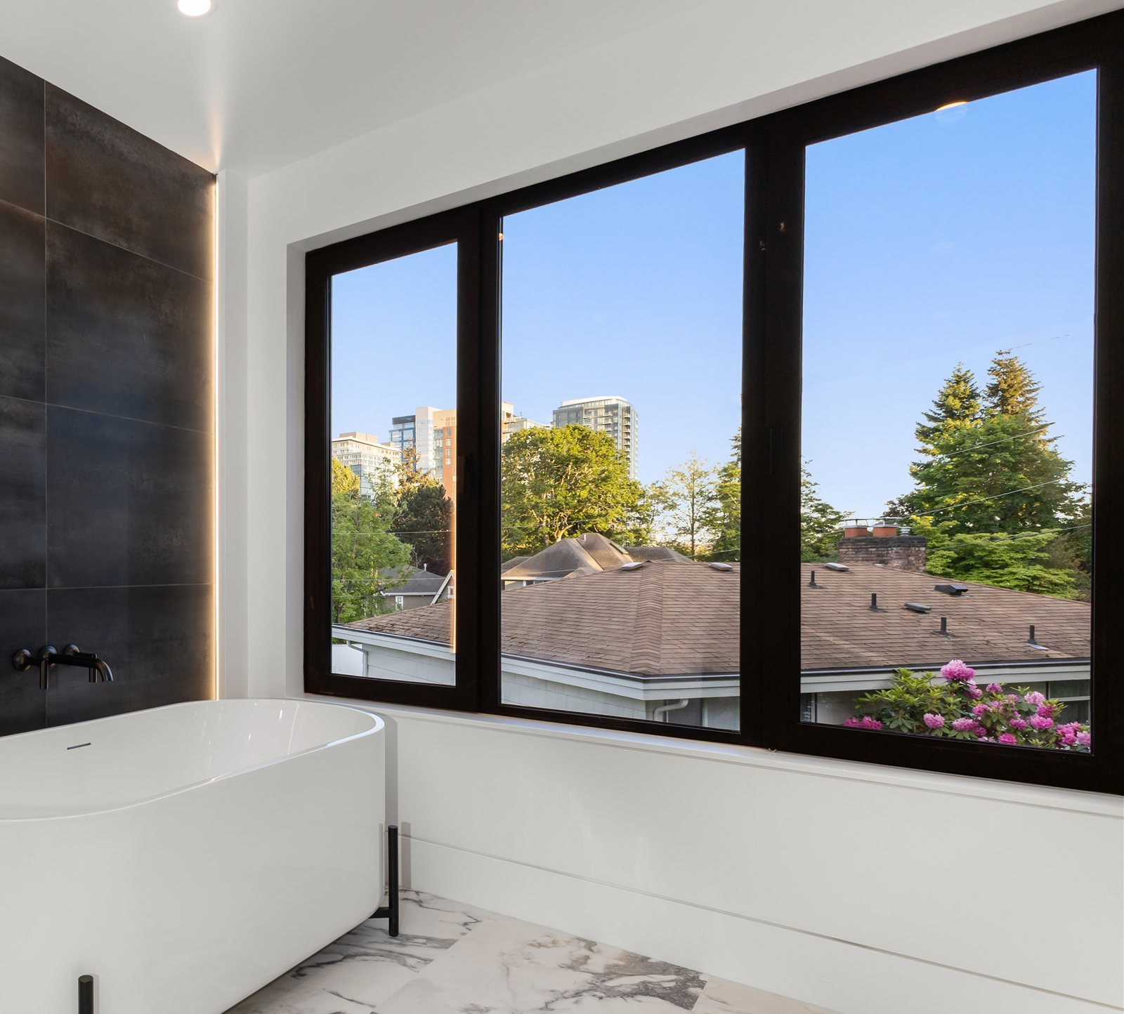 Primary bath with black-framed corner windows and skyline views